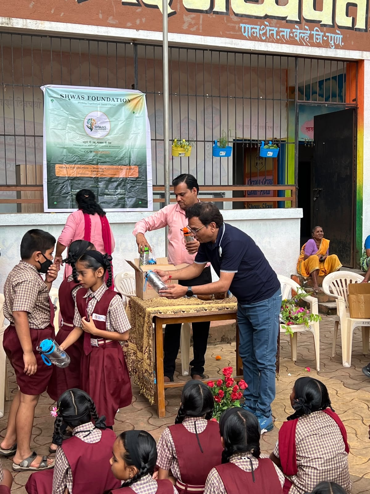 A foundation member distributing a water bottle to a student